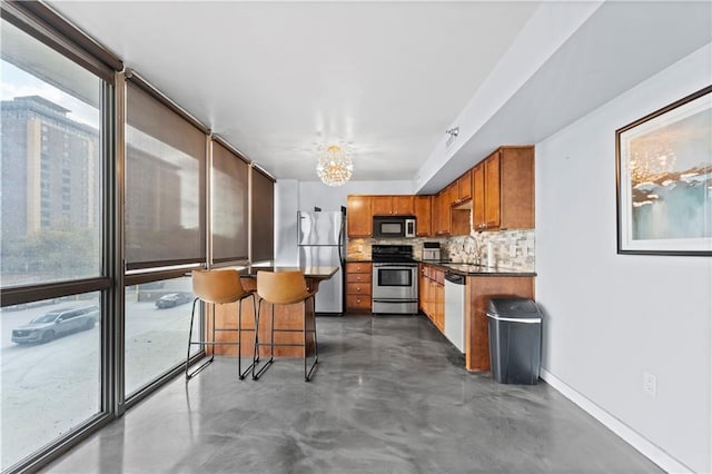 kitchen featuring stainless steel appliances, concrete flooring, a notable chandelier, and plenty of natural light