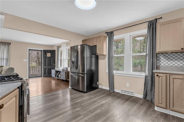 kitchen with dark hardwood / wood-style flooring, light brown cabinets, decorative backsplash, and stainless steel appliances