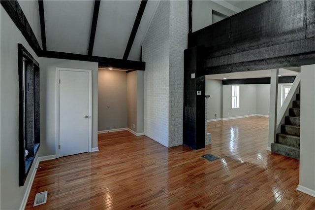 interior space with brick wall, high vaulted ceiling, beamed ceiling, and wood-type flooring