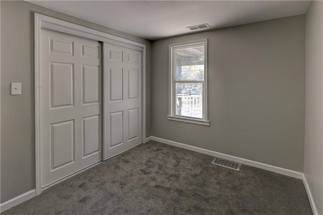 unfurnished bedroom featuring a closet and dark colored carpet