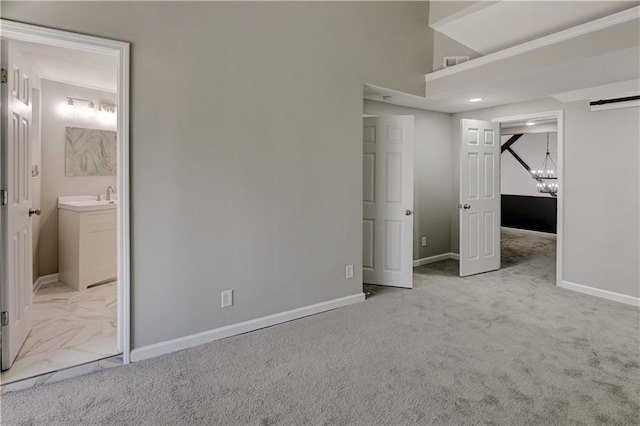 unfurnished bedroom featuring ensuite bathroom, light carpet, and sink