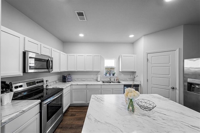 kitchen featuring sink, white cabinetry, stainless steel appliances, light stone counters, and dark hardwood / wood-style floors