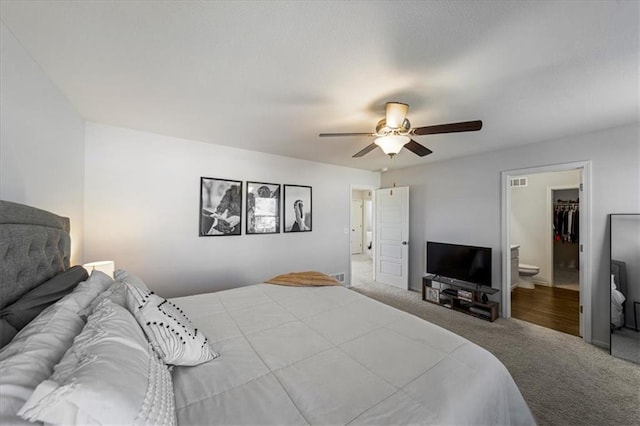 carpeted bedroom featuring a closet, a spacious closet, ensuite bathroom, and ceiling fan