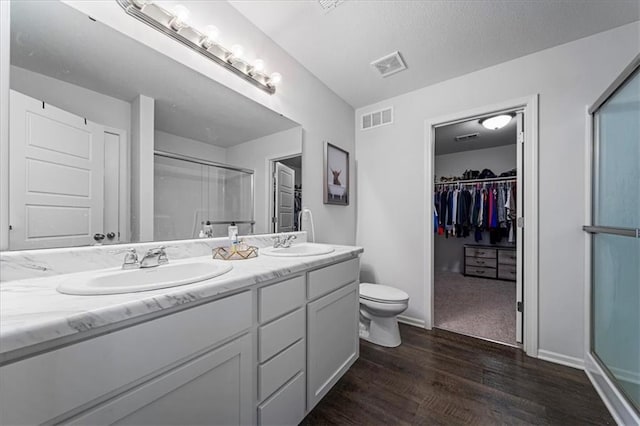 bathroom with vanity, toilet, hardwood / wood-style flooring, and a shower with shower door