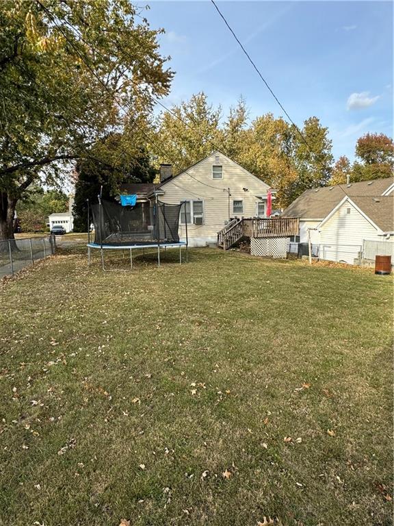 view of yard with a trampoline and a deck