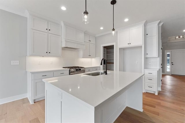 kitchen featuring white cabinetry, a kitchen island with sink, and stainless steel range with gas stovetop