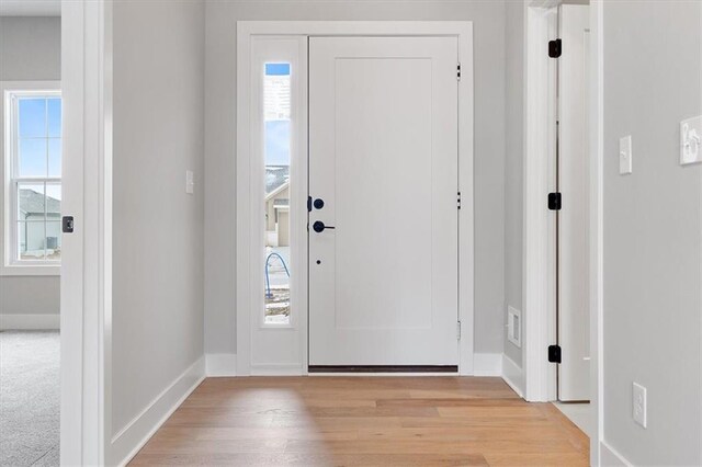 foyer entrance with light wood-type flooring, visible vents, and baseboards