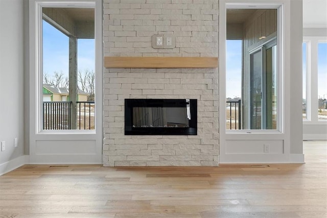 unfurnished living room featuring baseboards, wood finished floors, and a fireplace