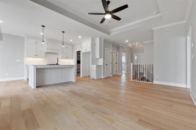unfurnished living room featuring light wood-type flooring, ceiling fan, baseboards, and ornamental molding