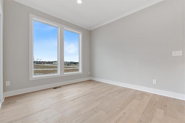 empty room with light wood finished floors, baseboards, and ornamental molding