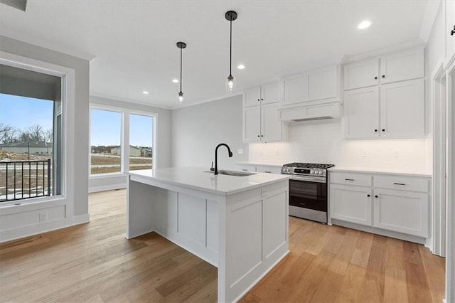 kitchen featuring decorative backsplash, stainless steel range with gas stovetop, a sink, and light wood-style flooring