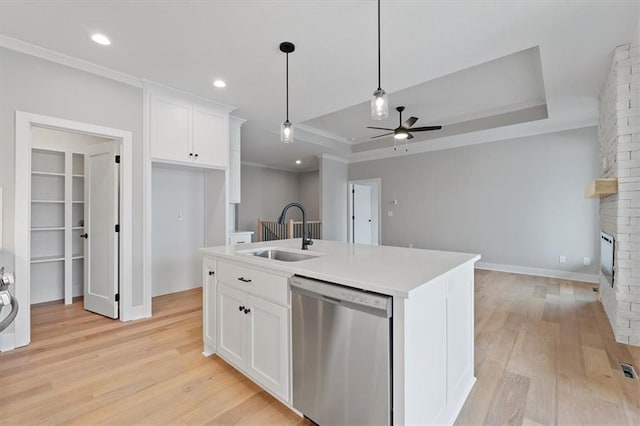 kitchen with stainless steel dishwasher, light wood-style flooring, a sink, a brick fireplace, and ceiling fan