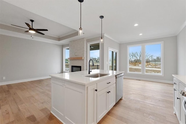 kitchen with crown molding, a sink, open floor plan, dishwasher, and light wood finished floors