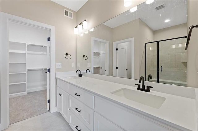 full bath featuring a spacious closet, visible vents, a stall shower, and a sink