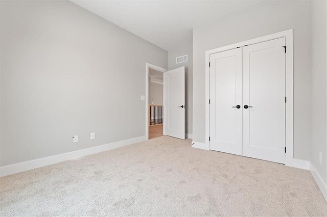 unfurnished bedroom featuring a closet, carpet floors, visible vents, and baseboards