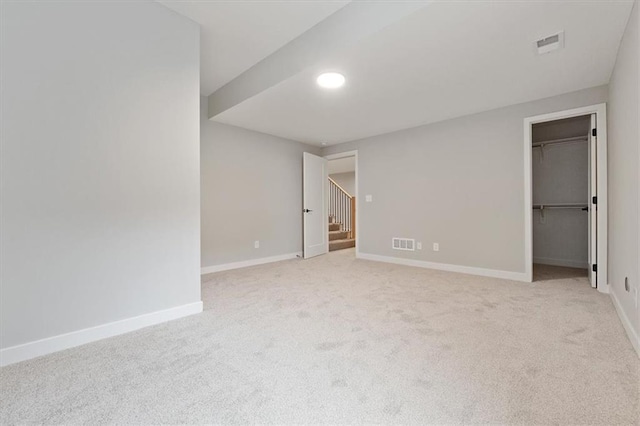 interior space featuring a spacious closet, baseboards, visible vents, and carpet floors