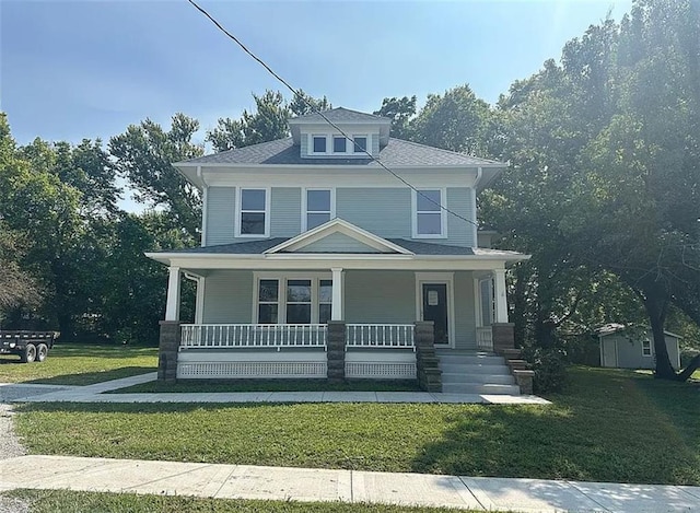 american foursquare style home featuring a porch and a front yard