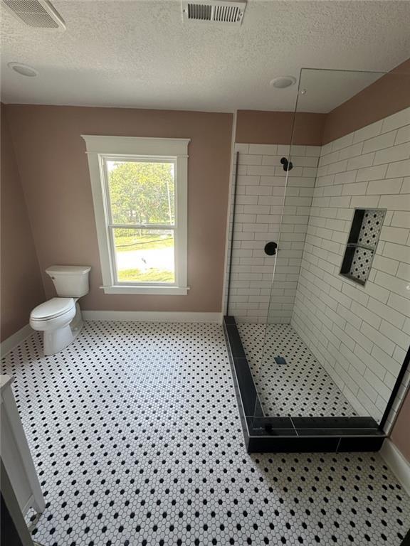 bathroom featuring toilet, visible vents, and tiled shower