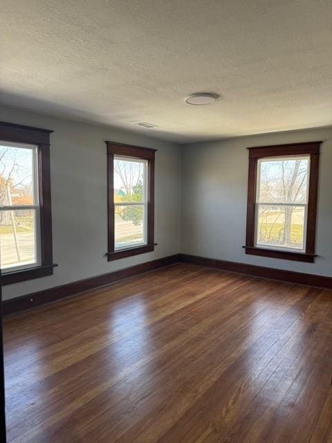 unfurnished room with dark wood-type flooring, plenty of natural light, and baseboards