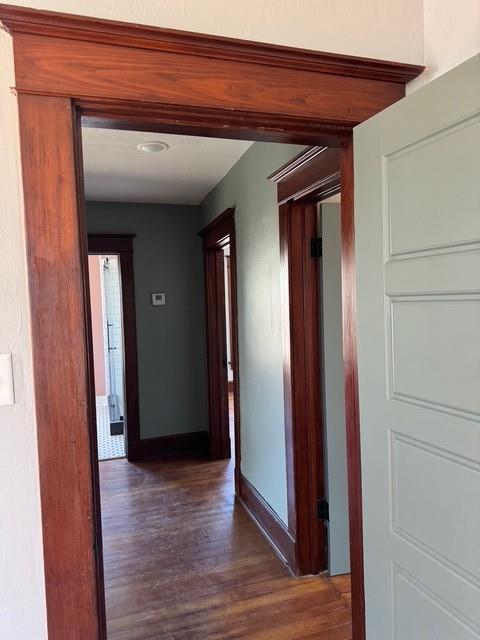 corridor with baseboards and wood finished floors