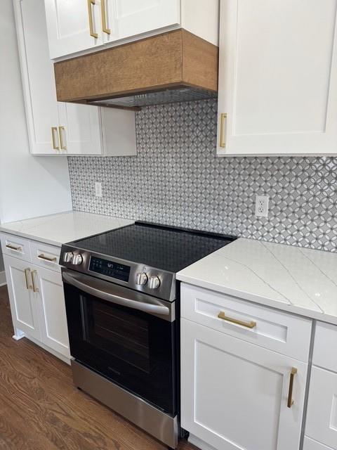 kitchen with electric range, tasteful backsplash, white cabinets, light stone countertops, and dark wood-style flooring