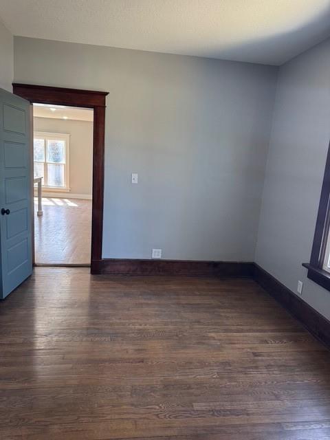 unfurnished room with dark wood-style floors, a textured ceiling, and baseboards