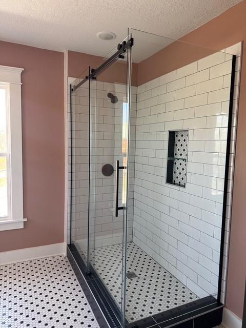 full bath featuring a shower stall, baseboards, and a textured ceiling