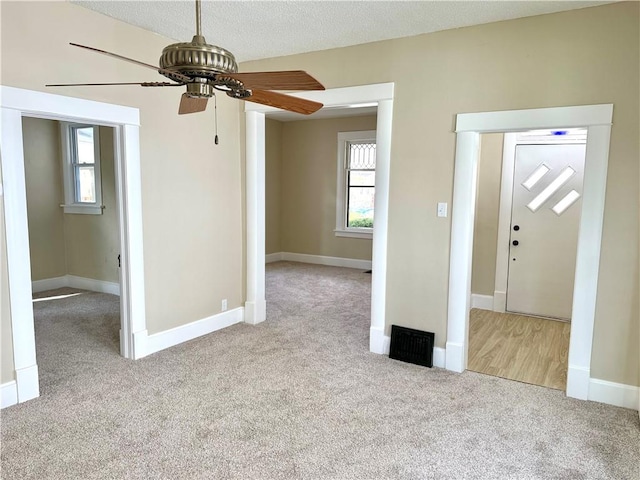 unfurnished living room with plenty of natural light, light colored carpet, and a textured ceiling