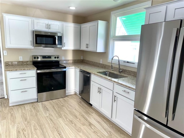 kitchen featuring white cabinets, sink, light hardwood / wood-style flooring, appliances with stainless steel finishes, and light stone counters