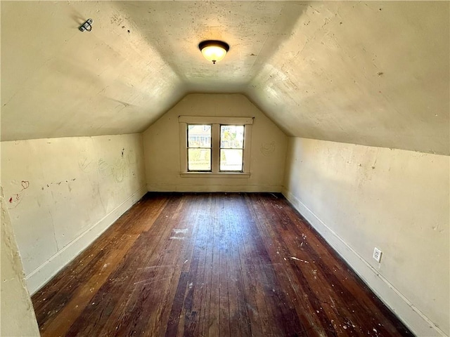 additional living space featuring dark wood-type flooring and vaulted ceiling