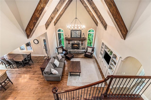 living room featuring high vaulted ceiling, a stone fireplace, beamed ceiling, and hardwood / wood-style floors