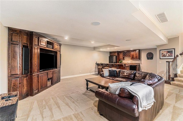 carpeted living room with a textured ceiling, ornamental molding, and indoor bar