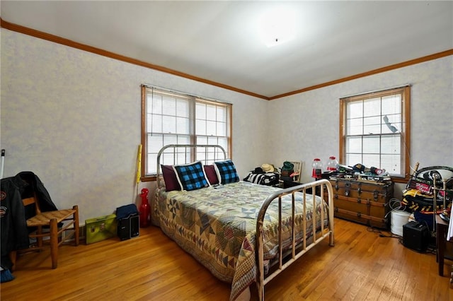 bedroom featuring ornamental molding, light wood-type flooring, and multiple windows