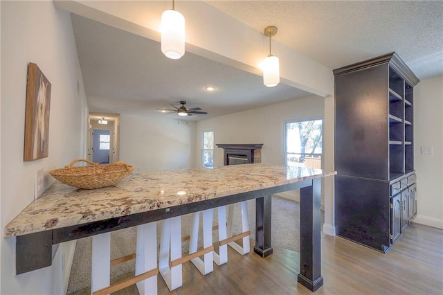 kitchen featuring kitchen peninsula, a textured ceiling, ceiling fan, hardwood / wood-style floors, and hanging light fixtures