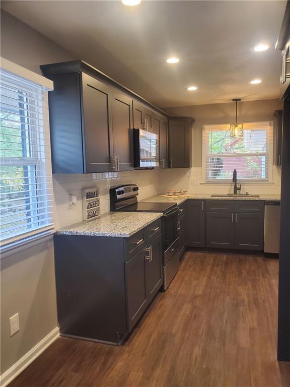 kitchen featuring dark brown cabinetry, sink, appliances with stainless steel finishes, decorative light fixtures, and dark wood-type flooring