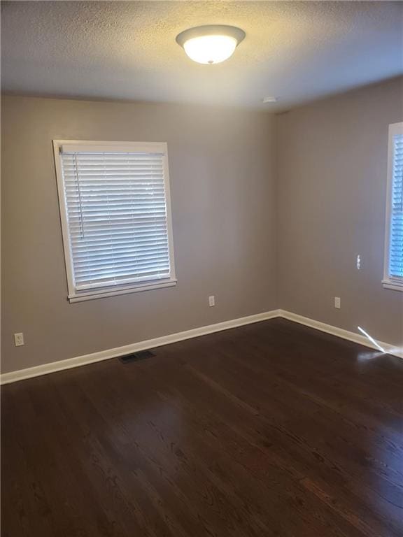 empty room with dark wood-type flooring and a textured ceiling