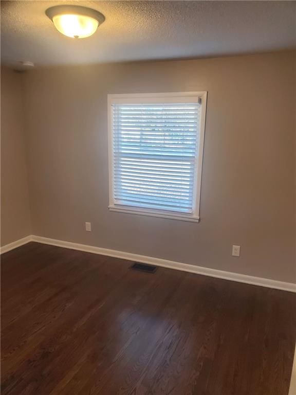 unfurnished room featuring dark hardwood / wood-style flooring and a textured ceiling