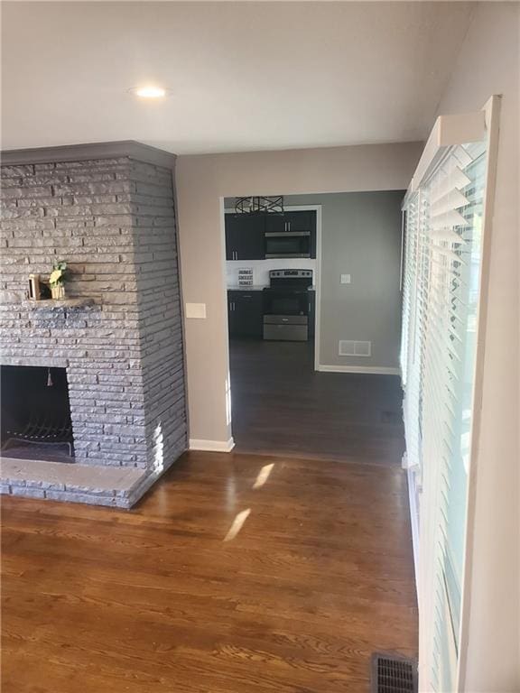 unfurnished living room featuring dark wood-type flooring and a stone fireplace