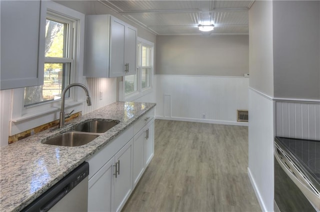 820 W Oak St, Chanute, KS 66720 - kitchen featuring a sink, stainless steel appliances, a wainscoted wall, light wood-style flooring, and white cabinets