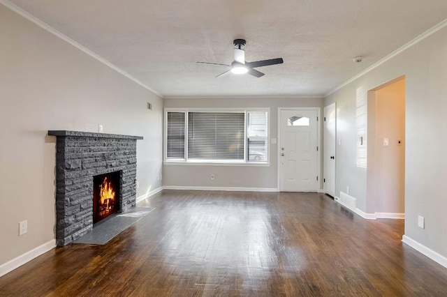 unfurnished living room with ceiling fan, a stone fireplace, ornamental molding, and dark hardwood / wood-style flooring