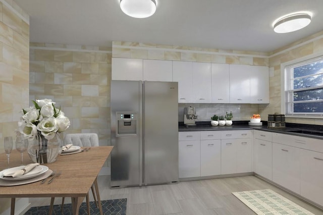 kitchen featuring white cabinetry, stainless steel refrigerator with ice dispenser, and tasteful backsplash