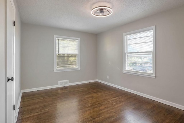 unfurnished room featuring a textured ceiling and dark hardwood / wood-style flooring