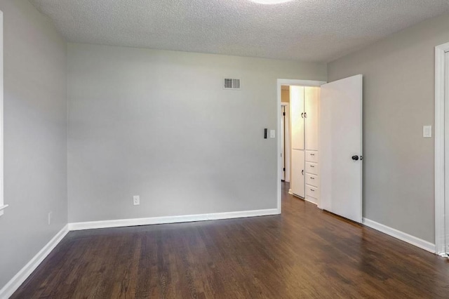 spare room with dark wood-type flooring and a textured ceiling