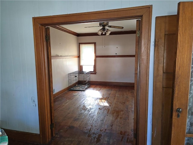 hallway featuring wood walls, crown molding, and dark wood-type flooring