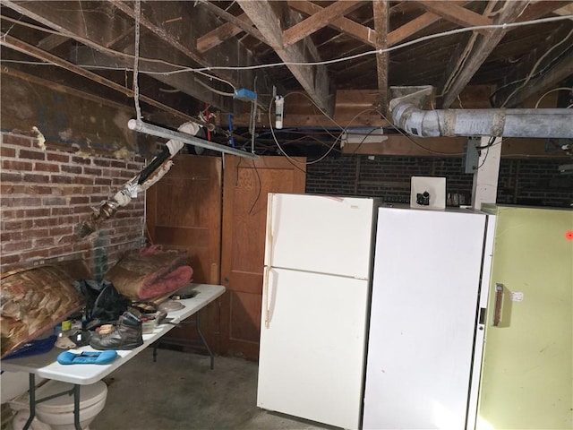 basement featuring white fridge and brick wall