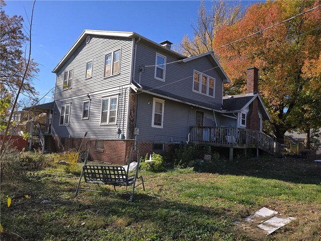 rear view of property featuring a yard and a wooden deck