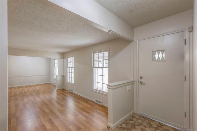 foyer entrance with a textured ceiling and light wood-type flooring