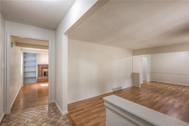 interior space featuring built in shelves, light hardwood / wood-style flooring, and a textured ceiling