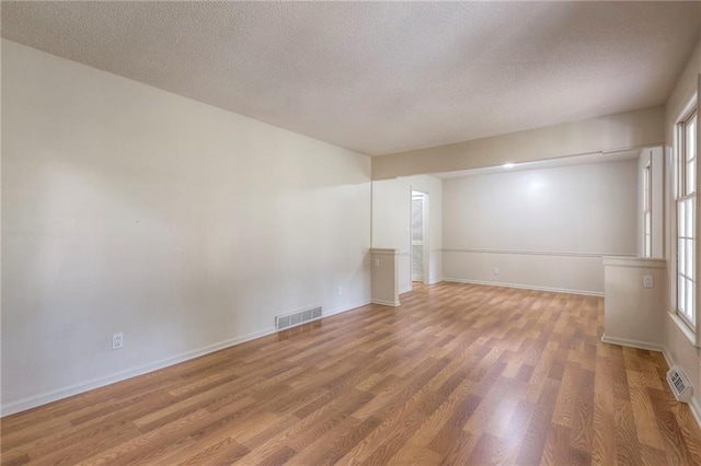 empty room with a textured ceiling and hardwood / wood-style flooring