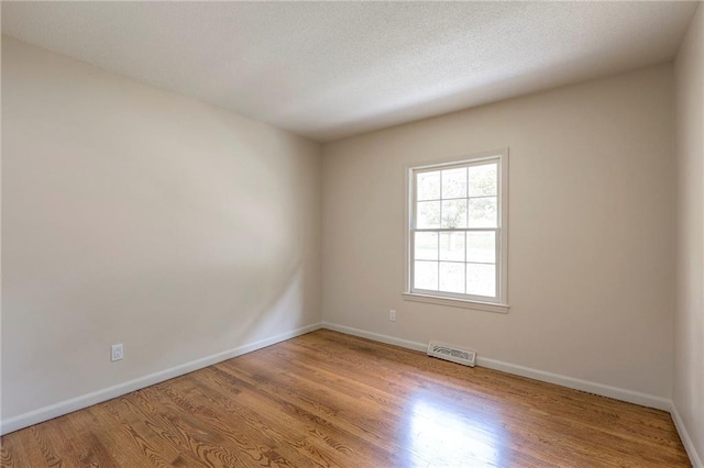 spare room featuring light hardwood / wood-style floors and a textured ceiling